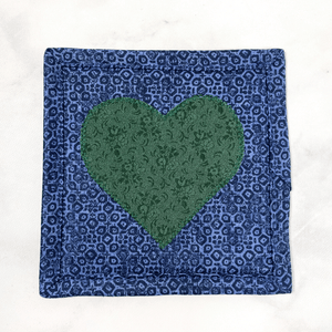 Mug rugs are also known as drink coasters. They are made from 100% cotton fabric, are insulated and washable too. These are great accessories for your home office desk or for your coffee bar area. This particular one is made with a blue background with a dark green appliqued heart in the center.