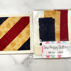 If you love craft kits, check out this quilt kit that will teach you how to make a fabric mug rug aka drink coaster.  Each kit comes with fabric plus printed directions and are mailed to your door.  This one is made with red, blue and yellow fabric.