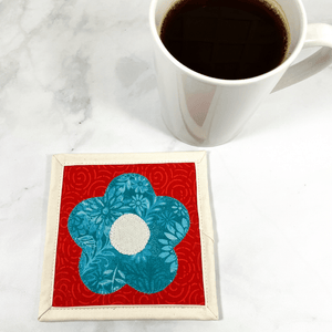 Mug rugs are also known as drink coasters.  They are made from 100% cotton fabric, are insulated and washable too.  These are great accessories for your home office desk or for your coffee bar area.  This particular one is aqua, red and cream with a flower applique in the center.