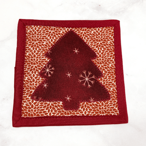 This is a mug rug aka drink coaster that has a gorgeous burgundy and cream Christmas tree applique pattern on the front.  These mug rugs make a great gift for the coffee lover in your life.  It brightens up any table or desk.