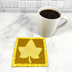 This is a maple leaf themed mug rug aka drink coaster with a yellow maple leaf that was appliqued to the front. These mug rugs make great gifts paired with the recipient's favorite coffee or wine. The bring a splash of color to any desk or table.