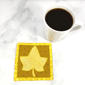This is a maple leaf themed mug rug aka drink coaster with a yellow maple leaf that was appliqued to the front. These mug rugs make great gifts paired with the recipient's favorite coffee or wine. The bring a splash of color to any desk or table.