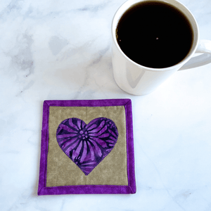This is a purple batik fabric heart mug rug. Mug rugs are also known as drink coasters.  They are made from 100% cotton fabric, are insulated and washable too.  These are great accessories for your home office desk or for your coffee bar area, adding a splash of color and uniqueness.