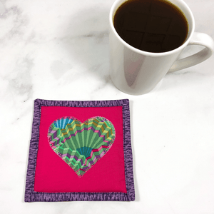 Mug rugs are also known as drink coasters.  They are made from 100% cotton fabric, are insulated and washable too.  These are great accessories for your home office desk or for your coffee bar area, adding a splash of color and uniqueness.  These are made with pink and purple fabric as well as fabric by Kaffe Fassett for the heart and the backing fabric.